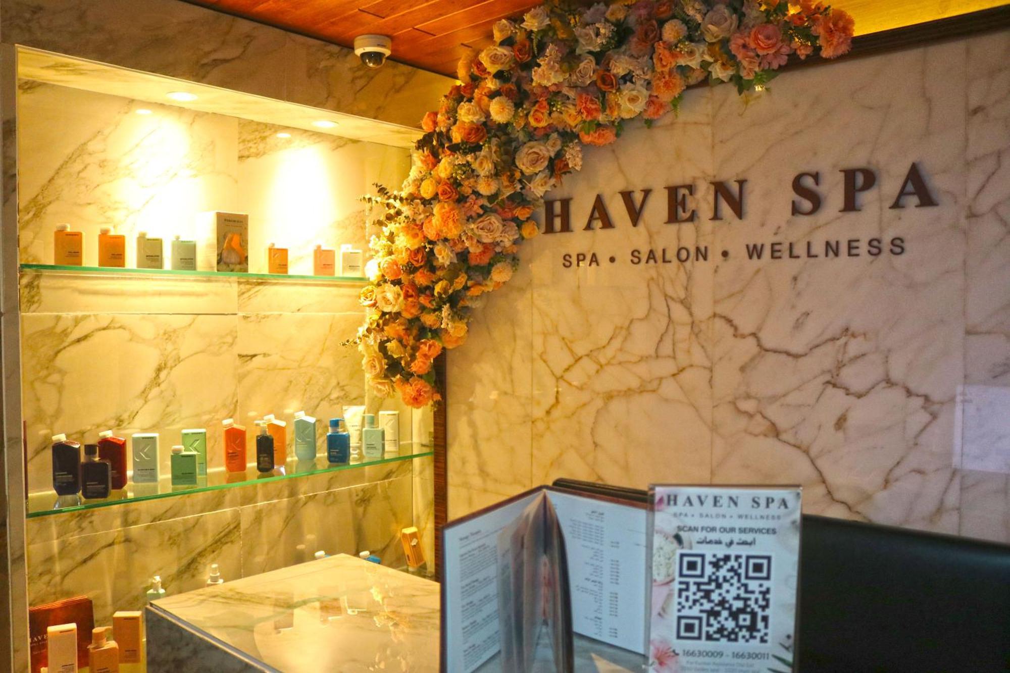 Lagoona Beach Luxury Resort And Spa Manama Luaran gambar The photo shows the interior of a spa called "Haven Spa." The wall is decorated with beautiful artificial flowers, creating an inviting atmosphere. There are several shelves displaying various colorful bottles and products, likely for skincare or wel