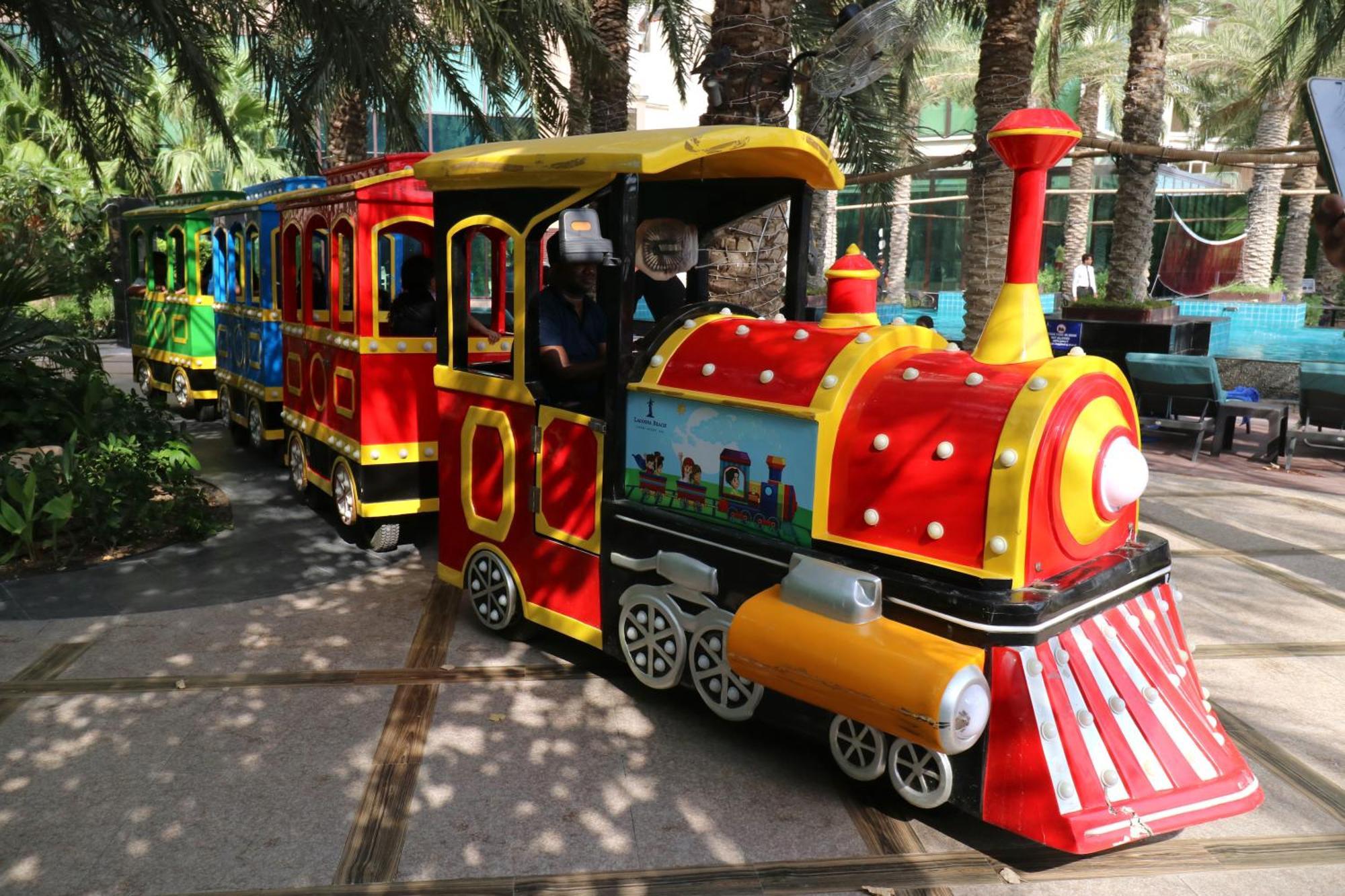 Lagoona Beach Luxury Resort And Spa Manama Luaran gambar The photo shows a colorful miniature train. It features a vibrant design with bright red, yellow, and blue colors. The front of the train resembles a classic steam engine, complete with a prominent smokestack. The train is designed to resemble a fun 