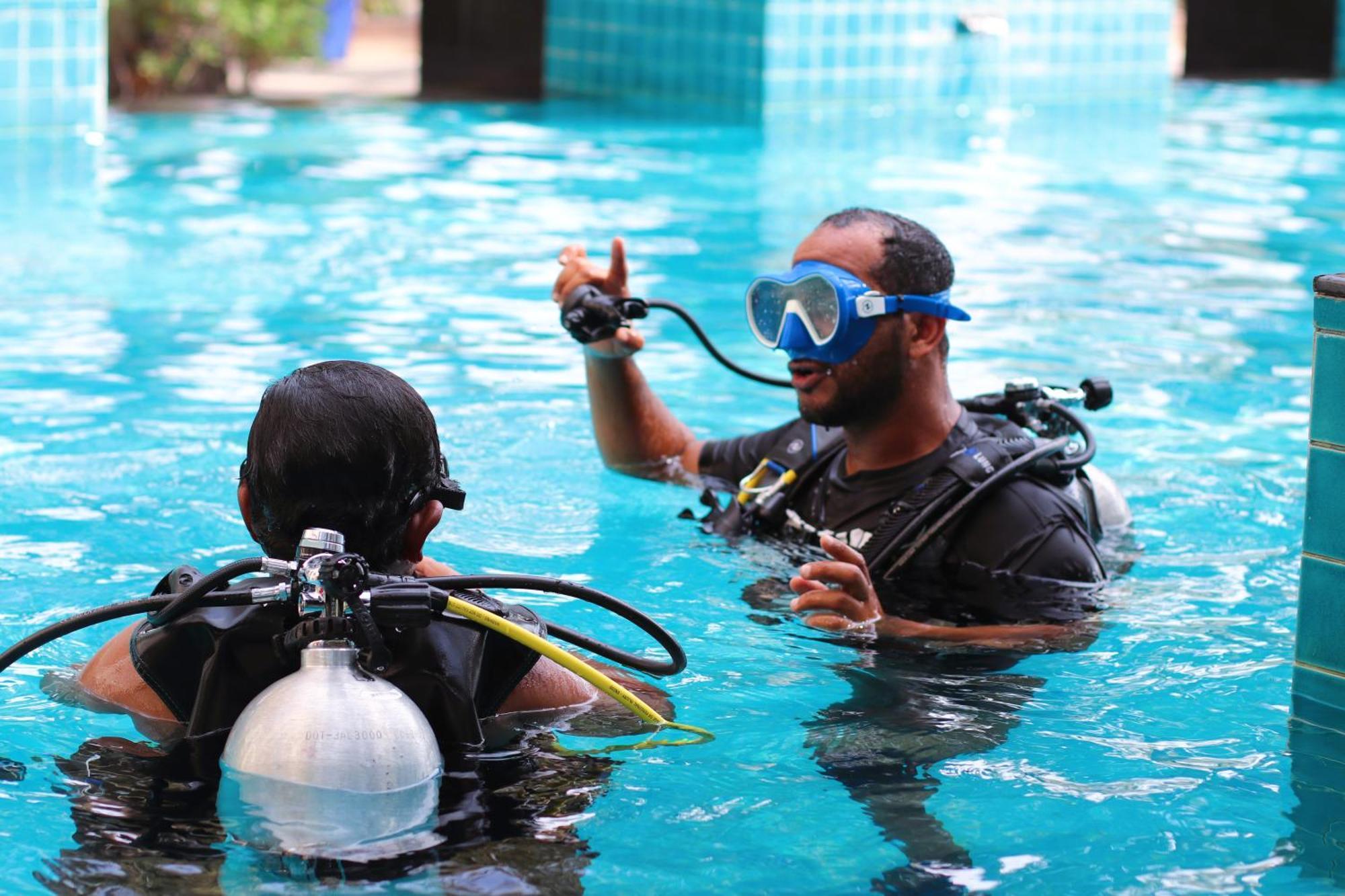 Lagoona Beach Luxury Resort And Spa Manama Luaran gambar The photo shows two divers in a pool. One diver is wearing a scuba mask and is speaking to the other diver, who is also equipped with scuba gear. They appear to be engaged in a discussion, possibly related to diving instructions or safety. The water 