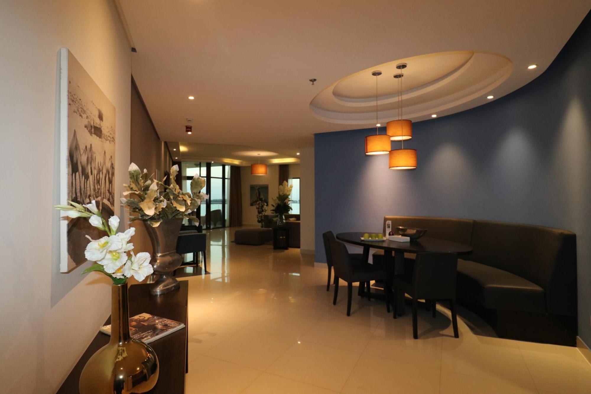 Lagoona Beach Luxury Resort And Spa Manama Luaran gambar The photo showcases an interior space, likely a modern lounge or reception area. It features a combination of soft lighting, neutral-colored walls, and decorative elements. There are elegant light fixtures hanging from the ceiling, and a curved blue 